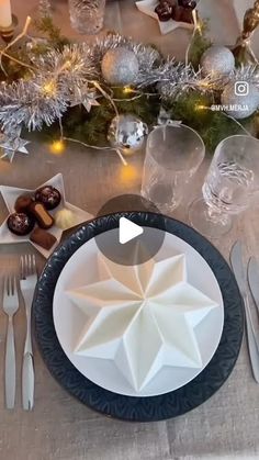 the table is set for christmas dinner with silverware and white napkins on it