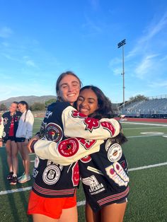 two girls hugging each other on a football field