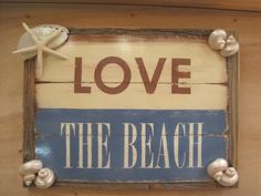 a wooden sign that says love the beach with shells and sea starfish on it