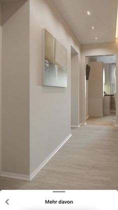 an empty hallway with white walls and wood flooring is shown in the foreground