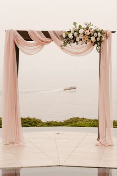 an outdoor ceremony setup with flowers and draping on the side, overlooking the ocean