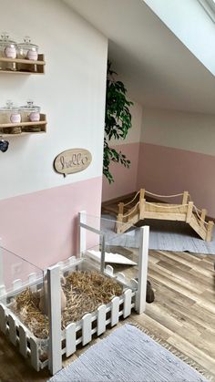 a room with pink and white walls, wooden flooring and shelves filled with hay