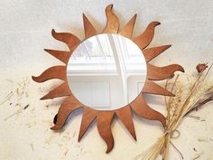 a mirror sitting on top of a table next to dried grass