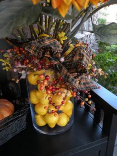 a glass vase filled with yellow fruit on top of a black table next to a window