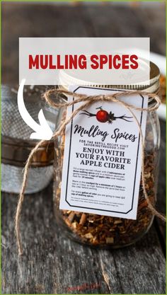 a jar filled with mulling spices sitting on top of a wooden table next to an apple