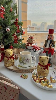 a table topped with christmas decorations and teddy bears next to a cup filled with chocolates