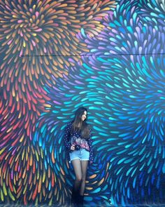 a woman standing in front of a colorful wall