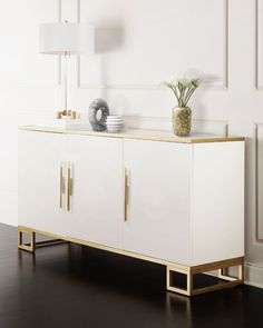 a white and gold sideboard with two vases sitting on it's sides