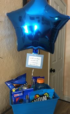 a balloon shaped like a star hanging from the ceiling over a blue box filled with candy