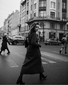 black and white photograph of woman walking across the street in front of people crossing the street