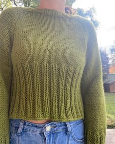 a woman wearing a green sweater and jeans