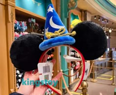 a person is holding up a mickey mouse ears headband with a hat on it