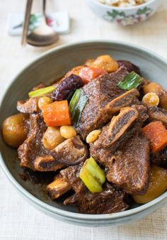 a bowl filled with meat and vegetables on top of a table next to a fork