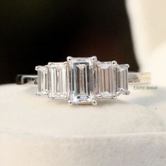 a three stone diamond ring sitting on top of a white cloth