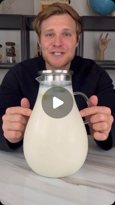 a man is holding up a jug of milk to show off it's contents