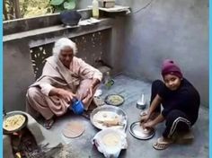 two people sitting on the ground with food in front of them and one person pouring water