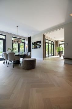 a living room filled with lots of furniture next to large windows on top of a hard wood floor