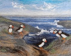 three puffins are standing on the rocks by the water