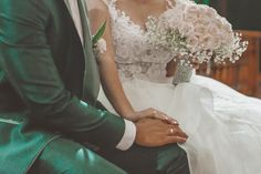 the bride and groom are sitting together in their wedding day attire, holding each other's hands