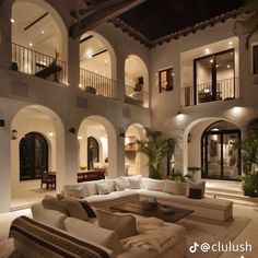 a living room filled with white furniture and lots of windows next to a staircase leading up to a second story