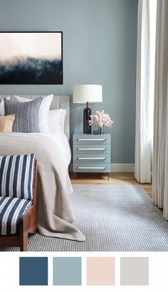 a bedroom with blue walls and white bedding, striped rugs, gray curtains, and a painting on the wall