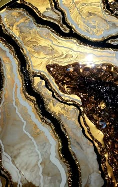 an abstract glass table top with gold and black swirling designs on the surface, reflecting light