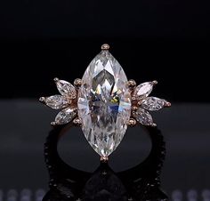 an engagement ring with a large pear shaped diamond surrounded by smaller pear - shaped diamonds