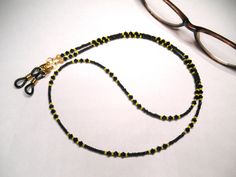 Length: 28"  Pittsburgh Steelers Football Team Eyeglass Chain Now you can show your team spirit by wearing this fun black and yellow beaded glasses chain! Composition: Premium Swarovski crystals in sparkling jet black (4mm) interspersed with black and yellow tiny glass seed beads.  Finished off with 2 small lobster clasps that allow you to interchange with different eyeglass ends if desired or connect both together and wear as a team necklace! Gold-plated components including wire guardians and fancy stardust crimp covers for a finished look.  Black eyeglass ends I only use professional high-strength and flexible beading cable in all of my creations. (multistrand wire with a nylon coating for a soft silky feel) This piece will arrive in either a pretty organza pouch or a cotton-filled gift Black Sports Jewelry With Round Beads, Adjustable Black Jewelry For Sports, Adjustable Beaded Black Glasses Chains, Adjustable Black Beaded Glasses Chains, Black Beaded Glasses Chain With Round Beads, Black Beaded Glasses Chains, Adjustable Black Glasses Chains For Gifts, Black Beaded Glasses Chains As Gift, Black Beaded Glasses Chains For Gift