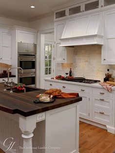 a large kitchen with white cabinets and wood counter tops, along with an island in the middle