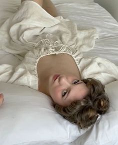 a woman laying on top of a white bed