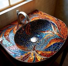 a bathroom sink that has a mosaic design on the top and bottom, along with a faucet