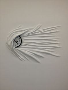 a clock that is on the side of a wall with long white streamers coming out of it