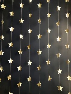 gold stars hanging from strings against a black wall