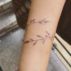 a woman's arm with a small branch tattoo on the left side of her arm