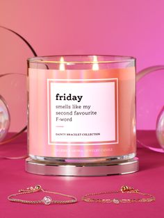 a candle that is next to some bracelets on a pink surface with the words friday spelled like my second favorite f word