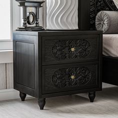 a black nightstand with two drawers and a clock on it's side table next to a bed