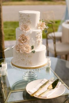 a three tiered white wedding cake sitting on top of a table next to a plate