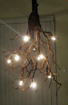 a chandelier made out of branches with lights hanging from it's sides