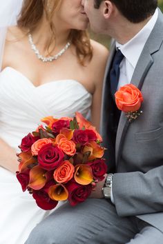 a bride and groom kissing each other with flowers in their lapel flower bouquets