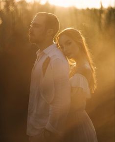 a man and woman standing next to each other in front of the sun shining down on them