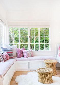 a white window seat with pillows on it and a rug in front of the window