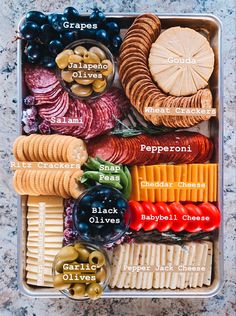 a plastic container filled with different types of cheeses and crackers on top of a table