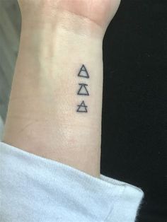 a woman's wrist tattoo with three symbols on the left side of her arm