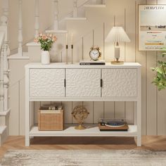 a living room with white furniture and flowers on the sideboard next to staircases