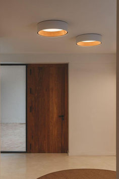 three circular lights are on the ceiling in an empty room with white walls and flooring