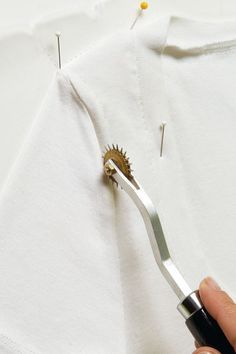 someone is using scissors to cut the fabric off of a white t - shirt with holes in it