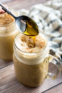 a spoon with some food in it on top of a jar and another cup filled with liquid