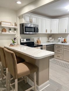 a kitchen with white cabinets and an island in the middle of the room that has four chairs around it