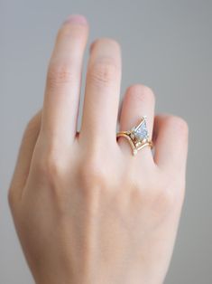 a woman's hand wearing a gold ring with a pear shaped diamond on it