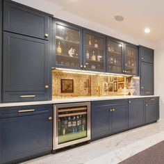 a large kitchen with blue cabinets and marble counter tops, along with a built in wine cooler